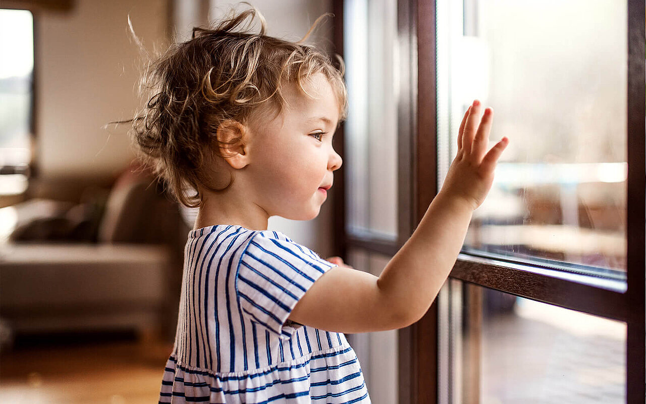Ein kleines Mädchen steht am Fenster 