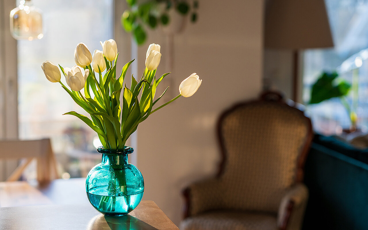 Eine blaue Vase mit Blumen im Wohnzimmer auf einem Tisch