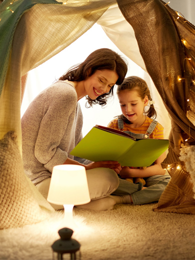 Ein Kinderzimmer in dem Mutter und Tochter unter einem Zelt gemeinsam ein Buch lesen