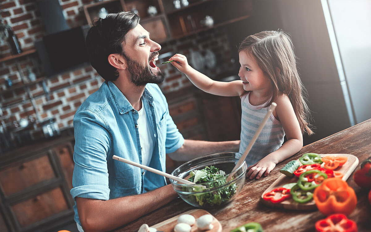 Eine Tochter gibt Ihrem Vater am Küchentisch mit Gemüse 