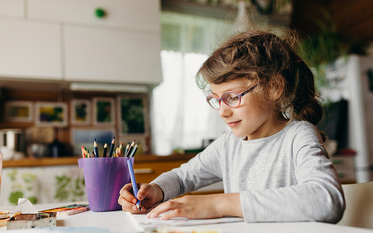 Ein Kind sitzt am Schreibtisch und malt