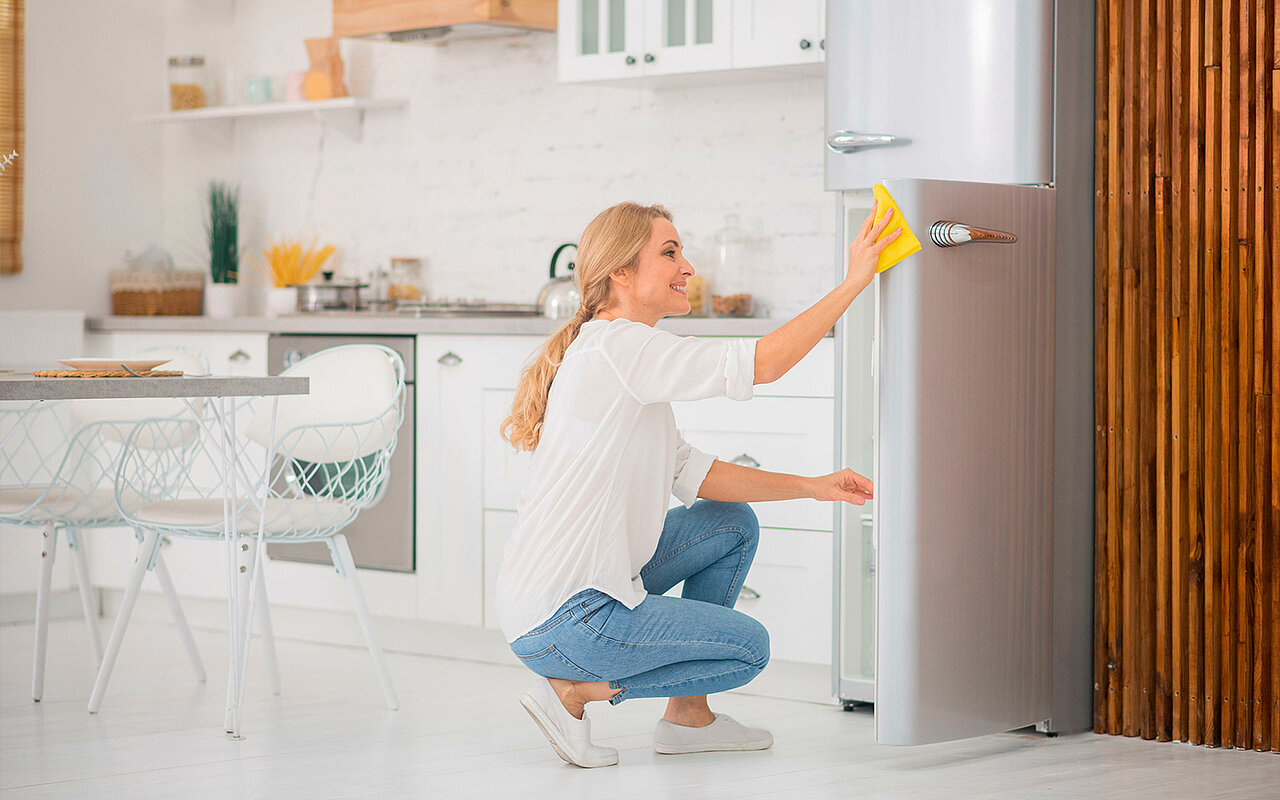 Eine Frau reinigt einen Kühlschrank 